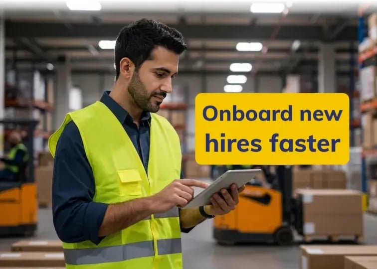 A man wearing a bright yellow high-visibility safety vest and a blue shirt stands in a warehouse setting. He is looking down and interacting with a digital tablet held in his hands. A yellow text box overlaid on the image reads: 