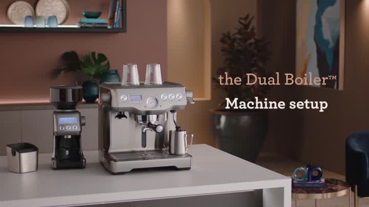 a consumer dual boiler espresso machine and a coffee grinder placed on a kitchen countertop