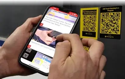 Knowby Track feature: A user scanning a QR code on machinery with a smartphone to access real-time reporting dashboards and compliance tracking.